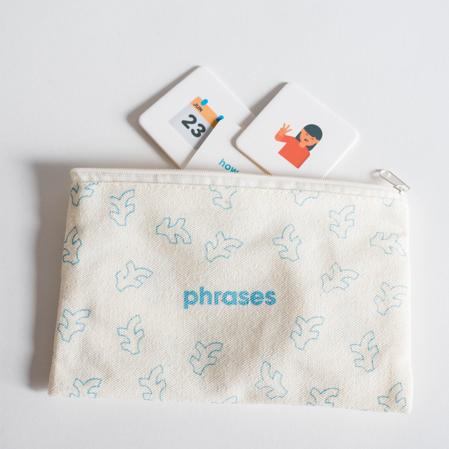 Cloth zippered Phrases Tile Pack pouch on white background with three tiles spilling out