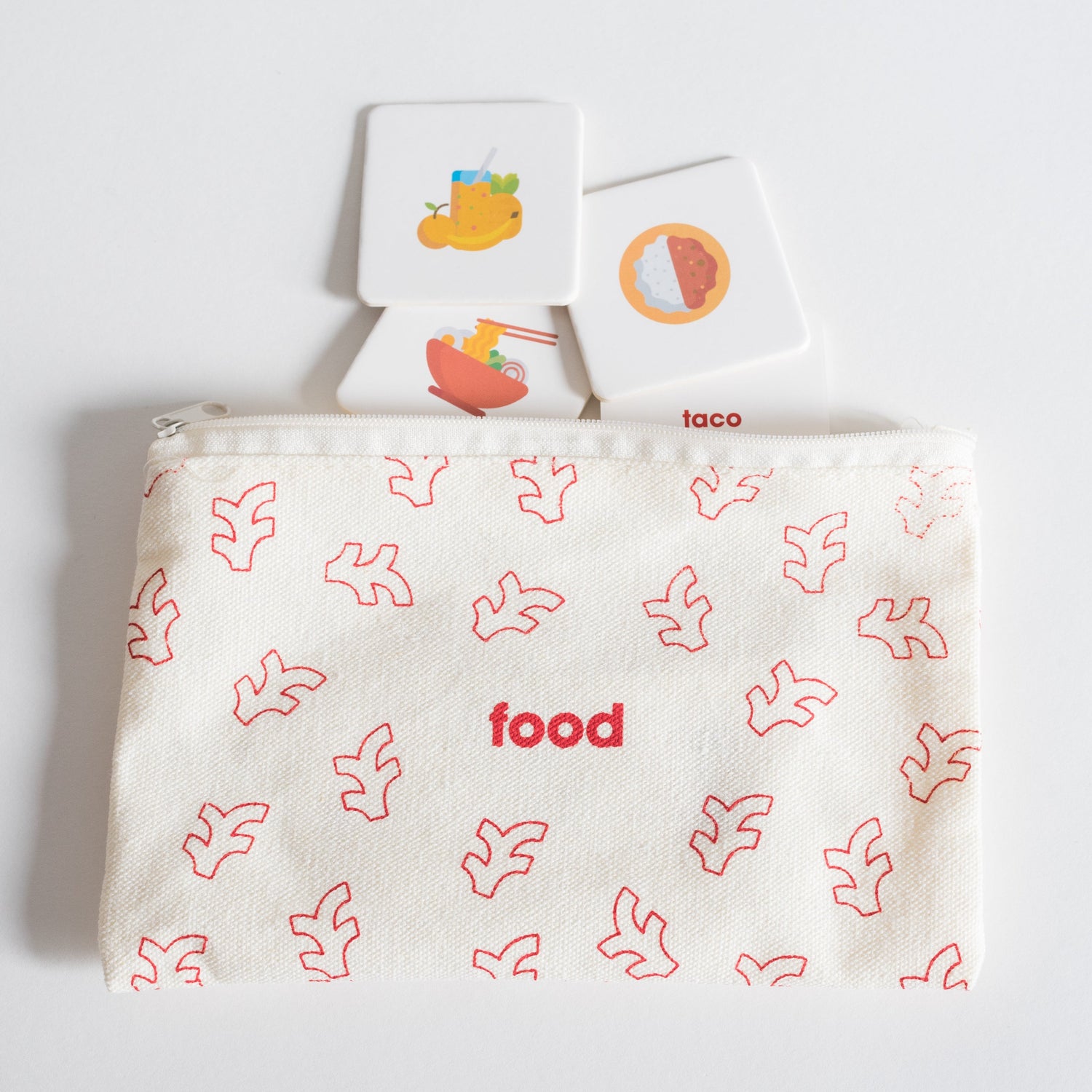 Cloth zippered Food Tile Pack pouch on white background with four tiles spilling out