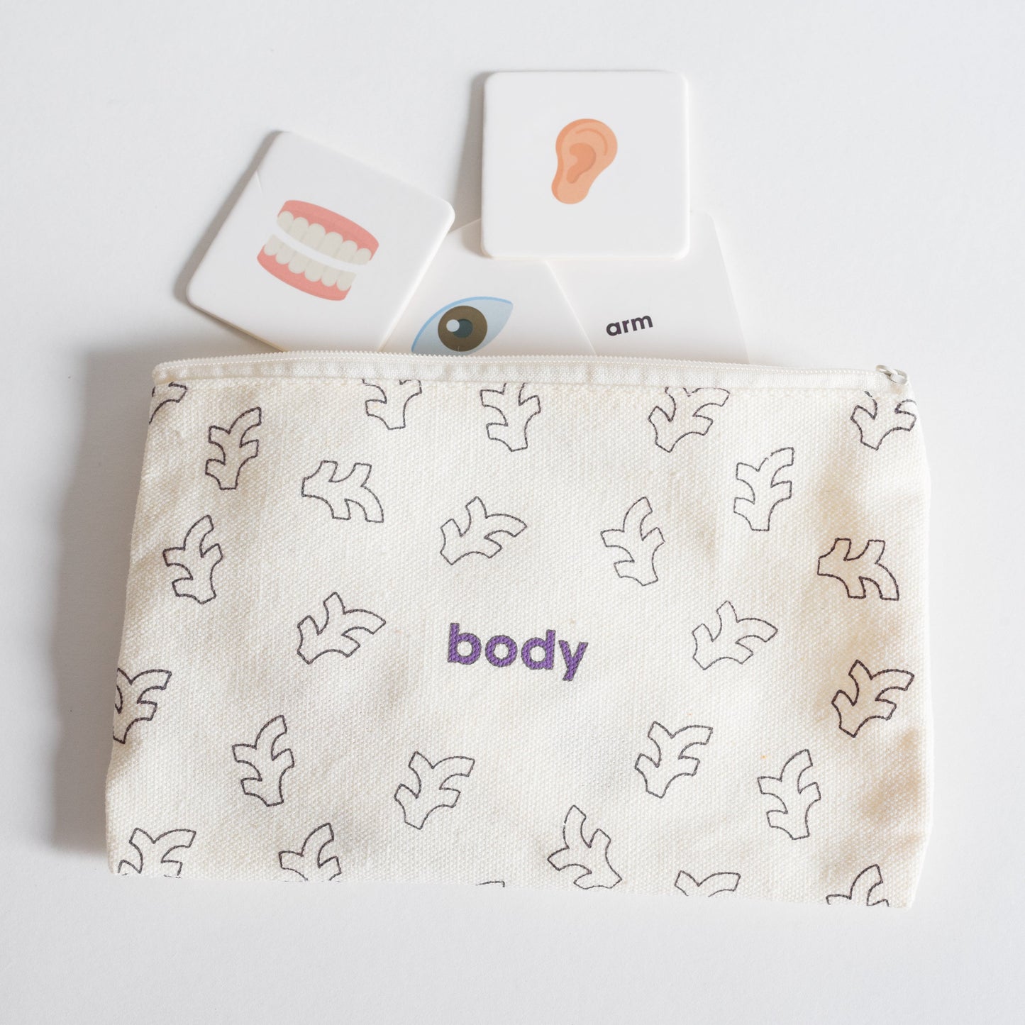 Cloth zippered Body Tile Pack pouch on white background with four tiles spilling out