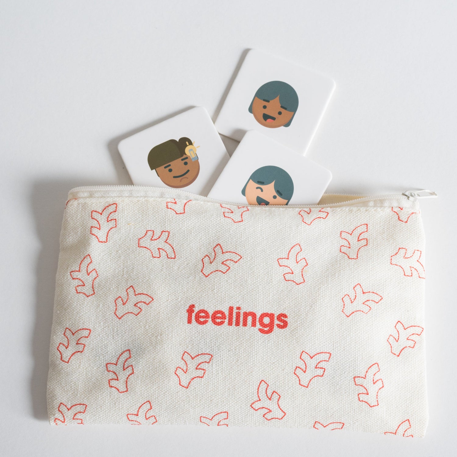 Cloth zippered Feelings Tile Pack pouch on white background with four tiles spilling out