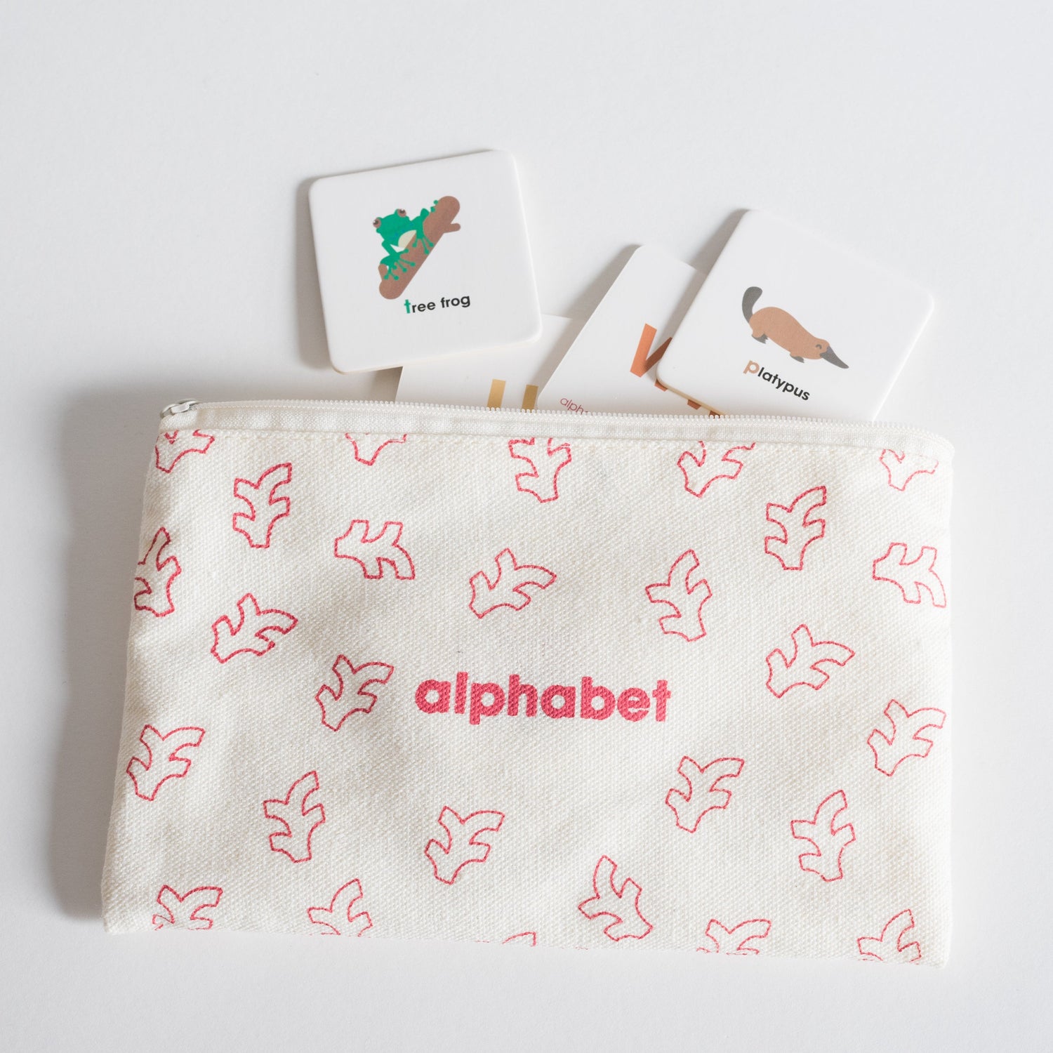 Cloth zippered Alphabet Tile Pack pouch on white background with four tiles spilling out